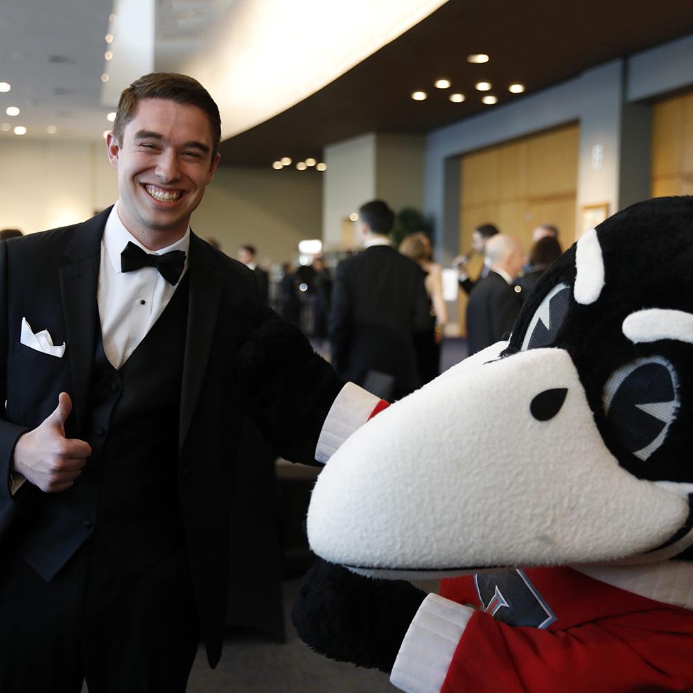 Scholarship Ball student speaker Jeff Schremmer poses with Rocky the Raven